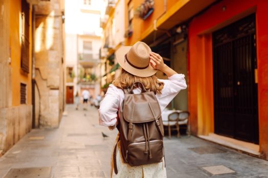 Beautiful,Tourist,Wearing,Hat,And,Carrying,Backpack,Strolls,Through,Narrow